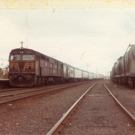 A Sydney to Brisbane passenger train beside cement wagons at Coffs Harbour Railway Station, c.1970s
