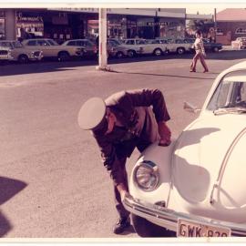 Parking officer marking tyres, corner of High and Castle Street, Coffs harbour, c. 1980s