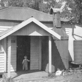 Child outside a house in Sawtell, 1958